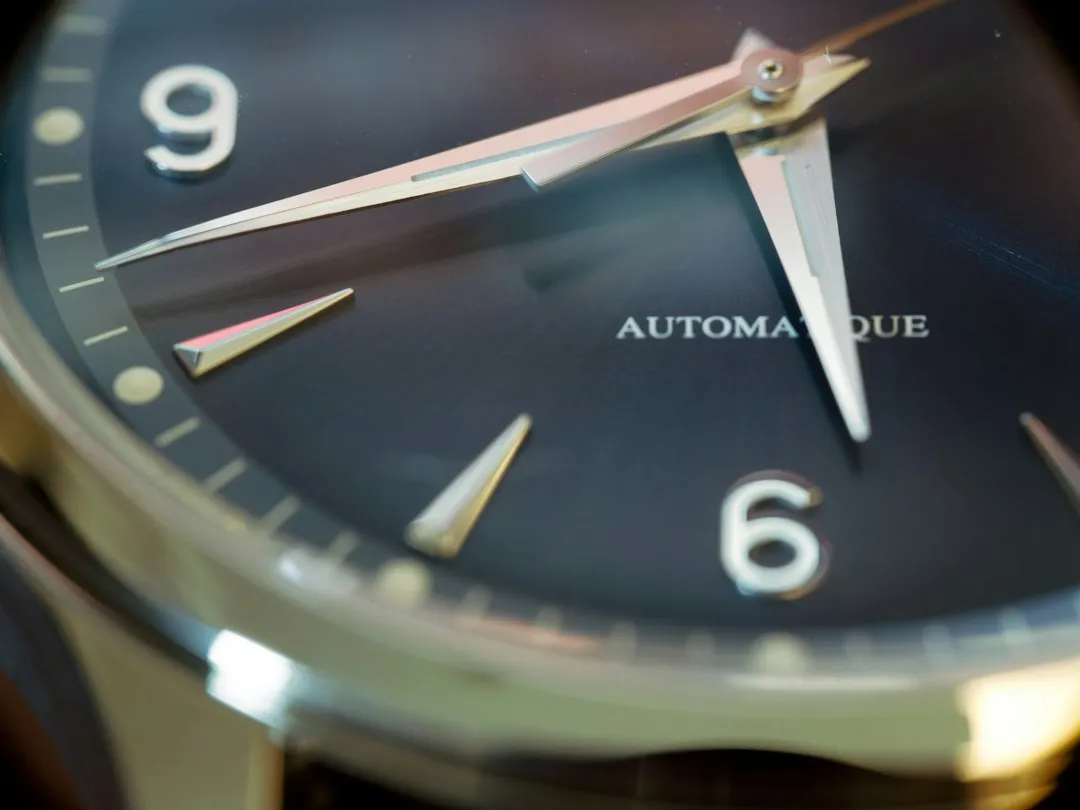 Close-up of a watch dial featuring automatic movement text and luminous hour markers.