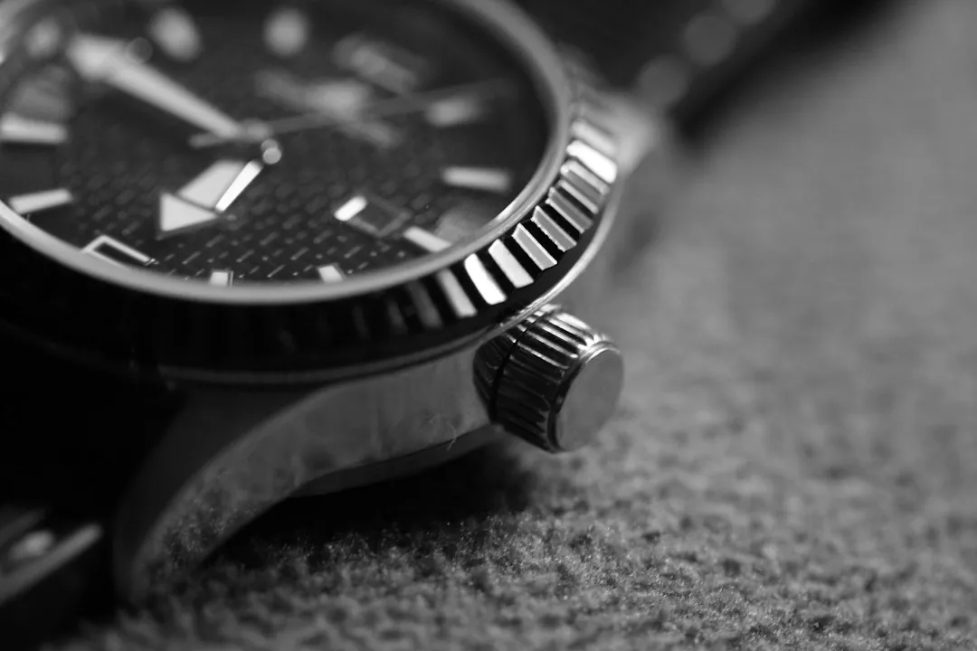 Un primer plano lateral de un reloj de pulsera que muestra una corona estriada para dar cuerda y ajustar la hora.