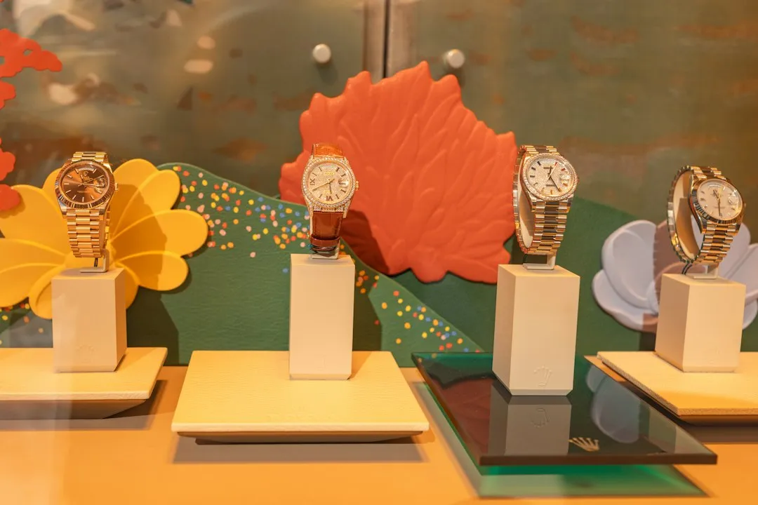 A row of gold Rolex Day-Date watches with President bracelets displayed on white pedestals.