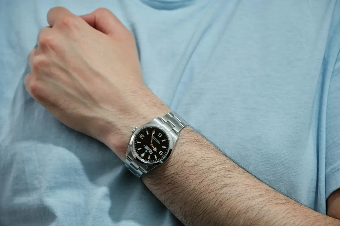 A close-up of a silver Rolex Explorer II watch with a black dial worn on a person's wrist.