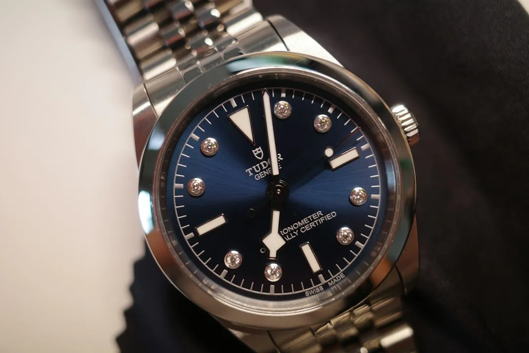 A close-up view of a Tudor Black Bay wristwatch featuring a blue dial and diamond markers on a steel bracelet.
