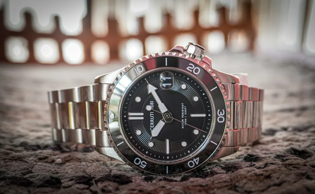 A close-up of a Tudor dive watch with a black unidirectional bezel resting on a dark surface.