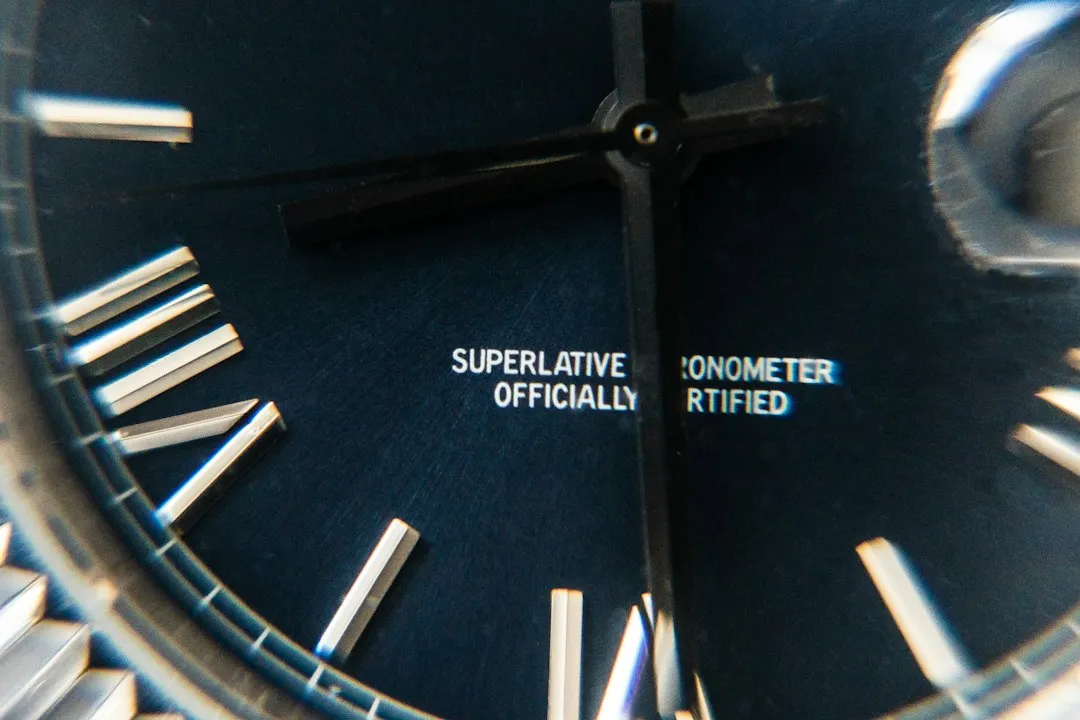 A close-up of a blue watch dial with a date magnifier lens visible on the right edge.