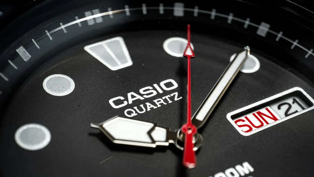 A close-up of a Casio watch dial featuring a date window at the 3 o'clock position reading SUN 21.