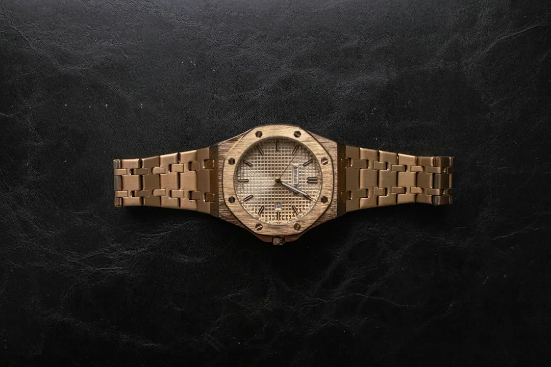 Un reloj Audemars Piguet Royal Oak de oro con bisel octogonal descansa sobre una superficie oscura.