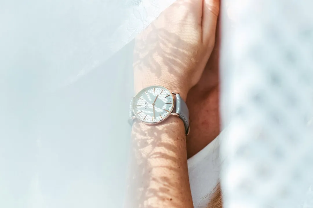 A close-up of a person's wrist wearing a silver analog watch with a white dial.