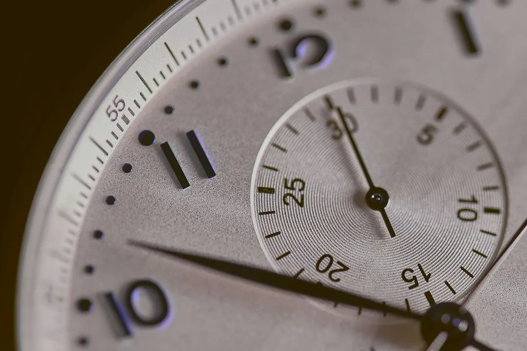 Close-up of a silver watch dial featuring a chronograph sub-dial and minute track.