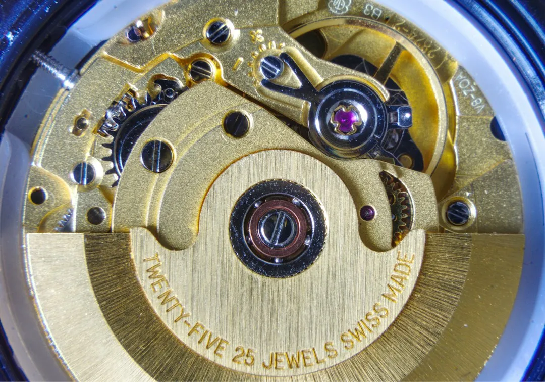 Close-up of a gold mechanical watch movement showing the rotor and Swiss made inscription.