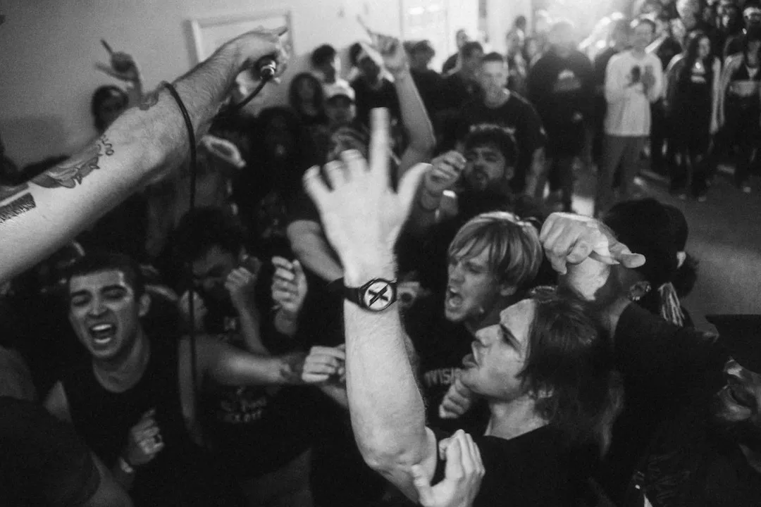 A person wears a rugged digital watch on their wrist amidst a crowd of people.