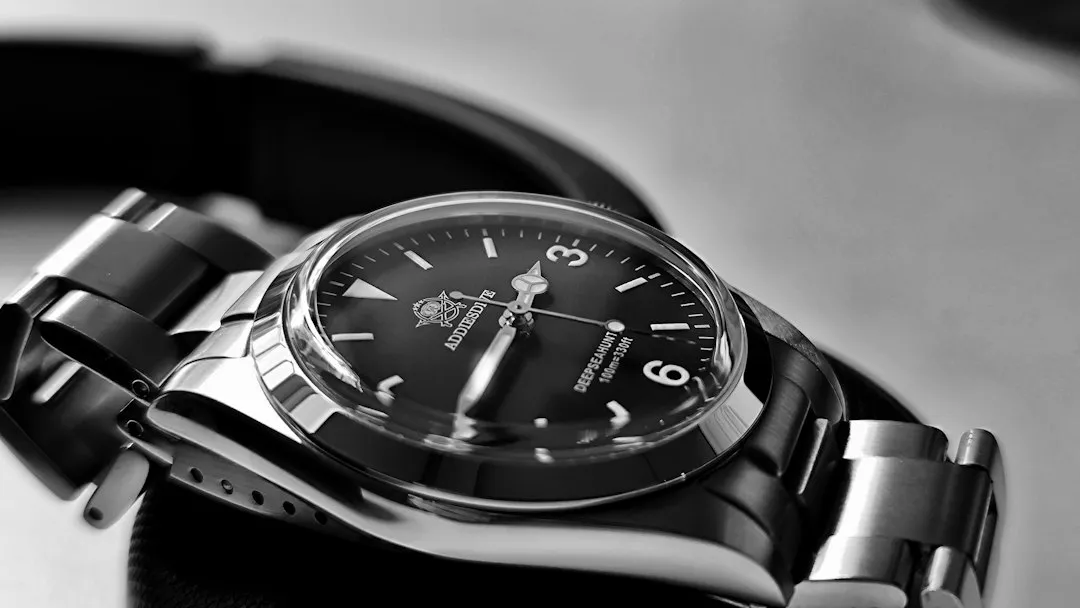 A black and white close-up of a vintage Rolex Explorer II wristwatch featuring a black dial and arrow-style hour hand.
