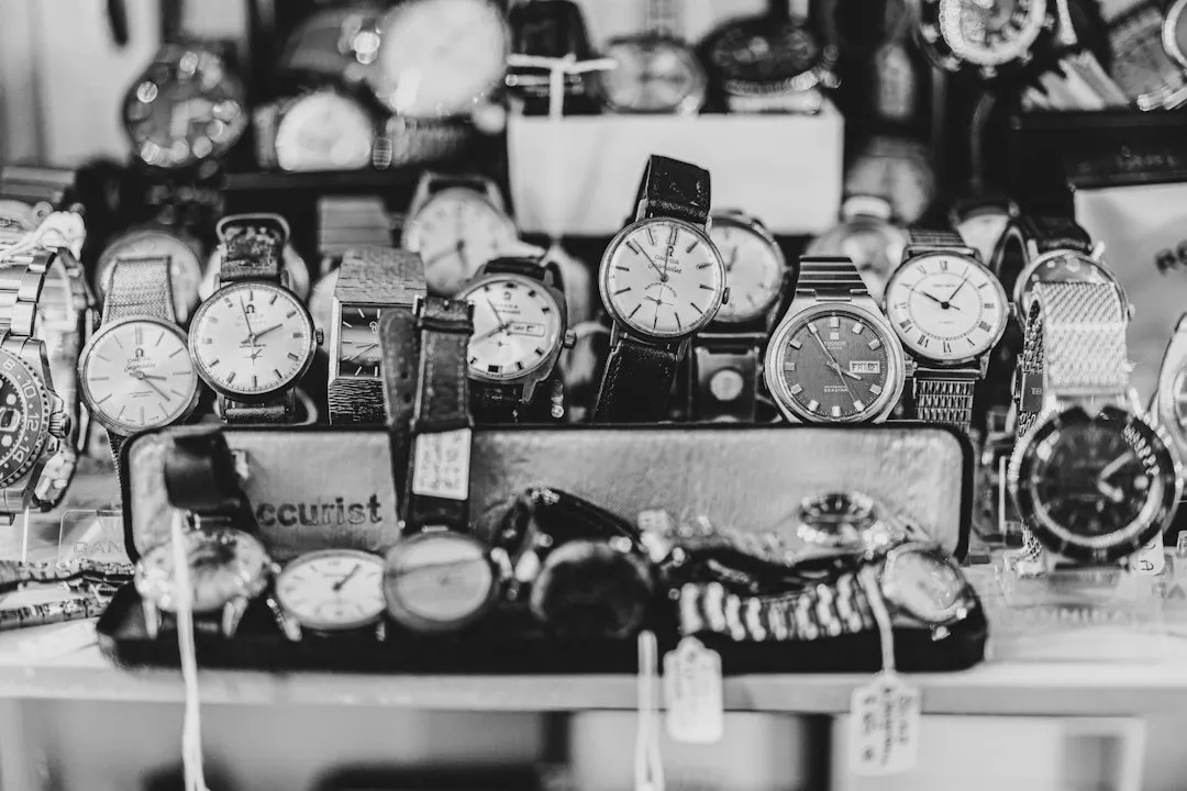 A black and white photo of numerous wristwatches arranged on a display tray in a shop window.