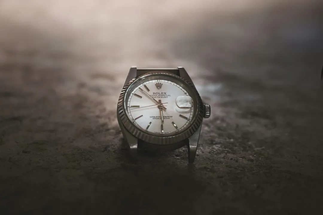 A close-up of a vintage Rolex watch with a fluted bezel resting on a dark surface.