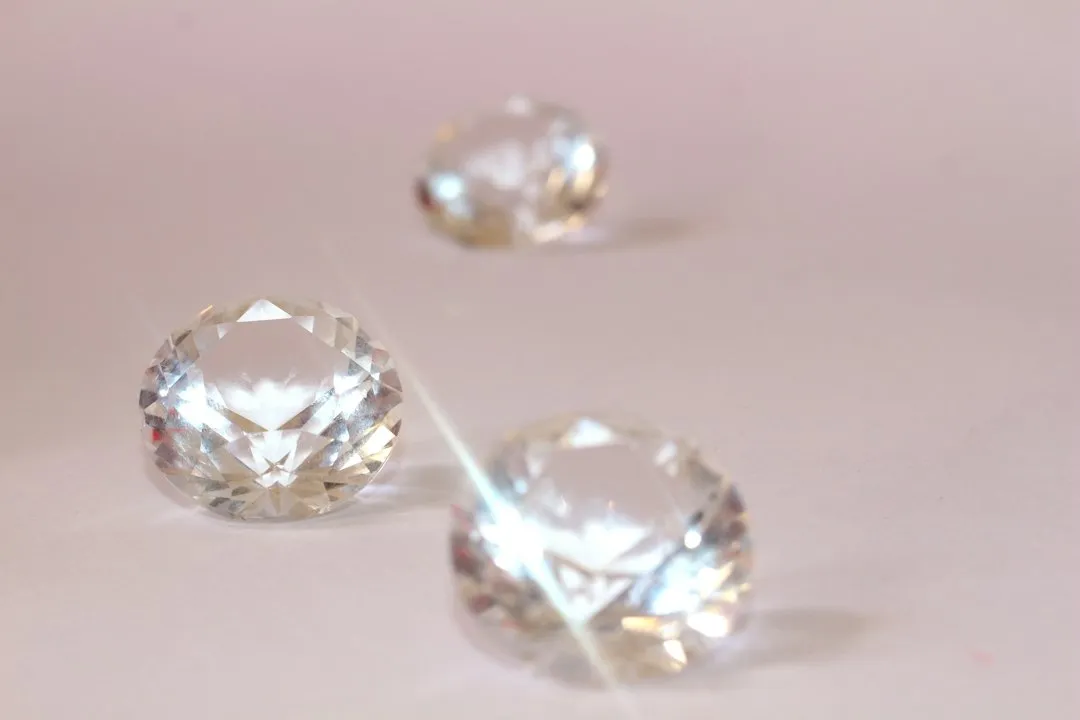Three clear, faceted sapphire watch crystals resting on a clean white surface.
